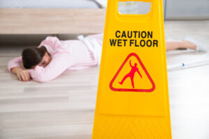 Slip and Fall Lawyer Washington DC - Wet Floor Sign With Fainted Housekeeper Lying On Floor